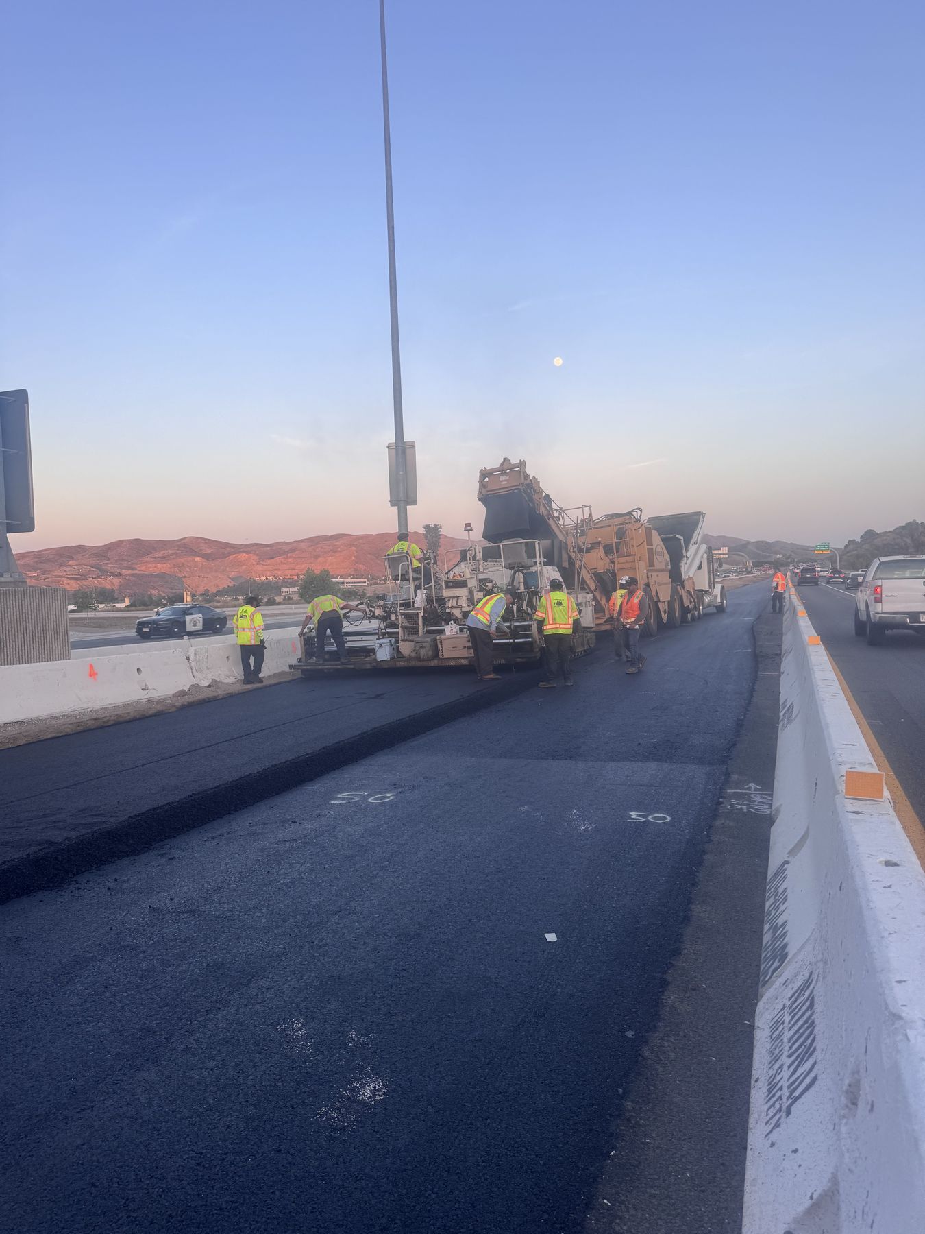 Freeway paving at sunrise behind k-rail